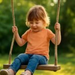 Kisgyermek hintázik a szabadban, mosolygós arccal.