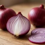 Friss lilahagyma és szeletei természetes háttér előtt.