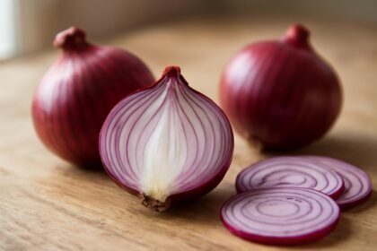 Friss lilahagyma és szeletei természetes háttér előtt.